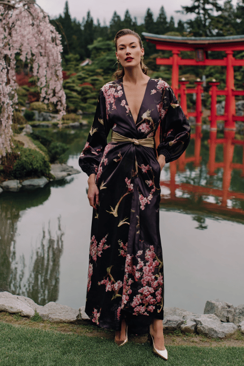 Elegant modest floral maxi dress outfit with long puff sleeves, a gold waist belt, and pointed heels in a Japanese garden with cherry blossoms and red torii gates