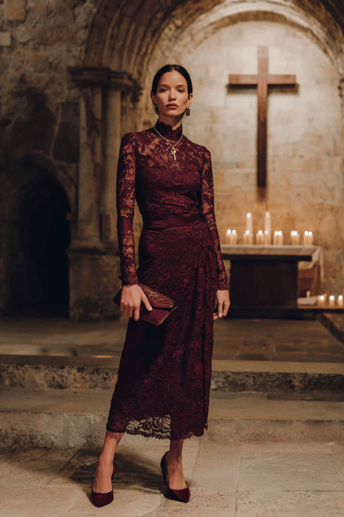 Elegant modest lace midi dress outfit with long sleeves, a high neckline, burgundy heels, and matching clutch inside a historic church