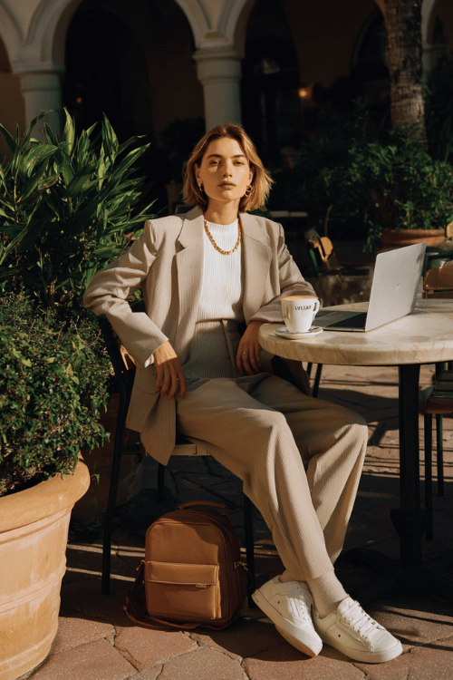 woman wearing a relaxed yet polished long-sleeve oversized blazer in soft warm beige layered over a fitted ribbed mock-neck top in ivory and wide-leg tailored trousers