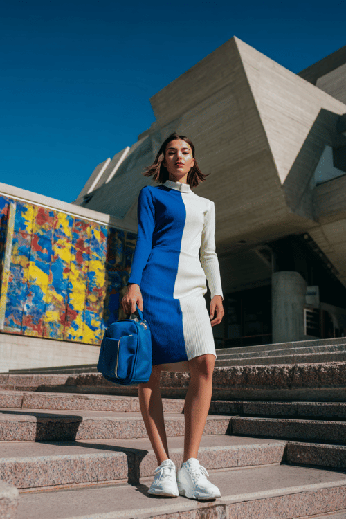 woman wearing a sleek long-sleeve color-block midi dress in bold cobalt blue and crisp white with a neat collar and structured silhouette, paired with white leather chunky sneakers