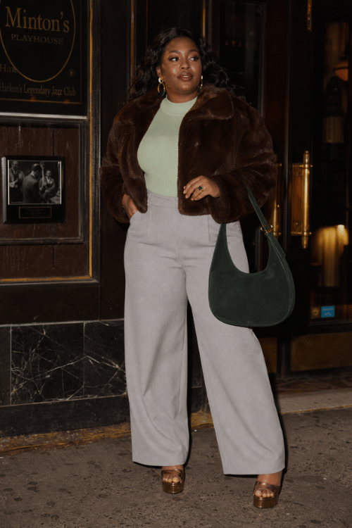 Plus-size woman wearing a brown faux fur jacket with gray wide leg trousers and platform sandals.