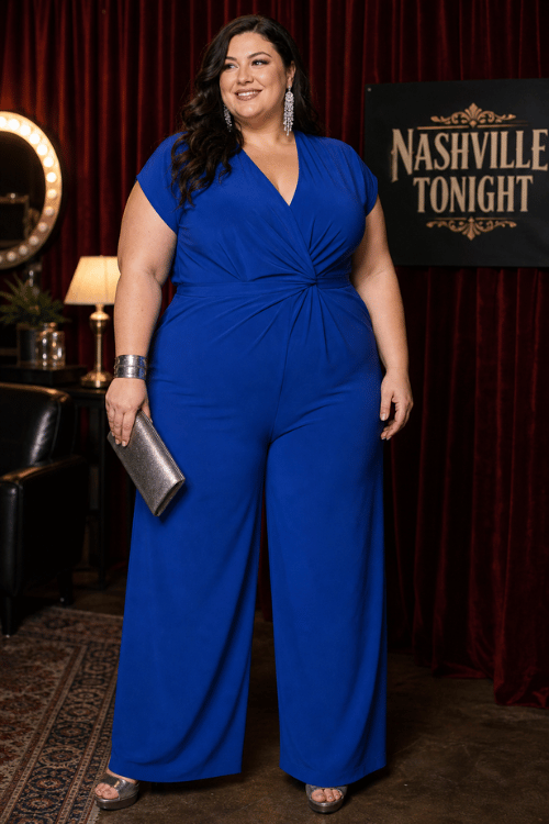 Plus-size woman wearing a royal blue wrap jumpsuit with silver heels and a metallic clutch in a Nashville lounge.