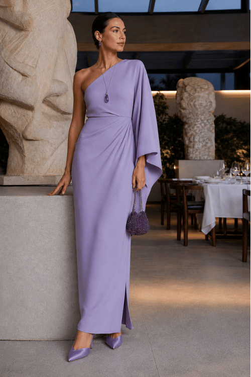 Woman in a lavender one-shoulder evening gown with matching heels and a beaded handbag.