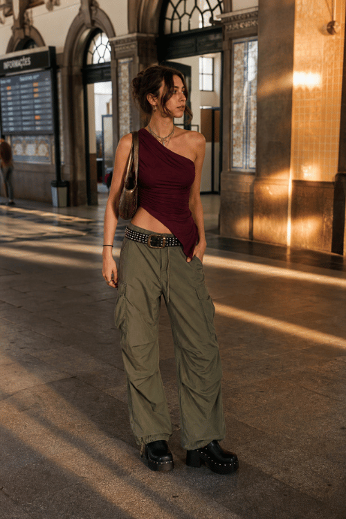 Woman wearing a burgundy one-shoulder top with olive cargo pants and platform boots.