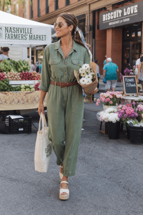 Woman wearing a sage green utility jumpsuit with platform sandals at the Nashville Farmers' Market.