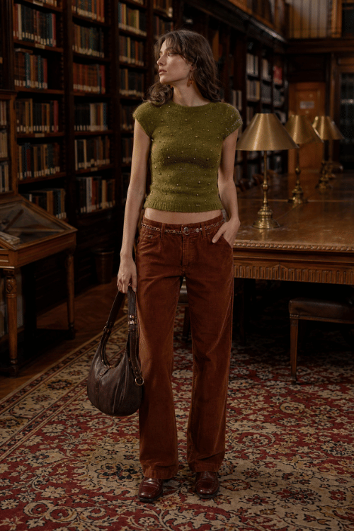 Woman wearing an olive knit top with brown corduroy pants and leather loafers.