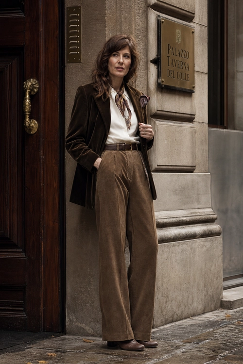 Brown Blazer and Wide-Leg Trousers A woman wears a dark brown blazer, white blouse, patterned neck scarf, and high-waisted brown wide-leg trousers with brown shoes.