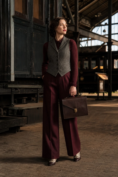 Burgundy Trousers with Tweed Vest A burgundy knit top and wide-leg trousers are styled with a gray tweed vest, dark shoes, and a structured brown handbag.