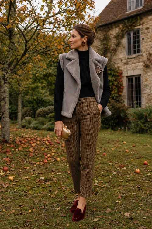 Layered Autumn Countryside Outfit A black ribbed turtleneck layered under a gray sleeveless vest with brown checked trousers, burgundy loafers, and a small gold clutch.