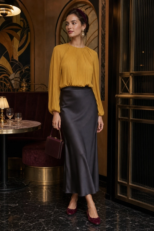 Mustard Blouse and Satin Midi Skirt Outfit A woman wears a mustard pleated blouse with a dark satin midi skirt, burgundy heels, and a matching structured handbag.